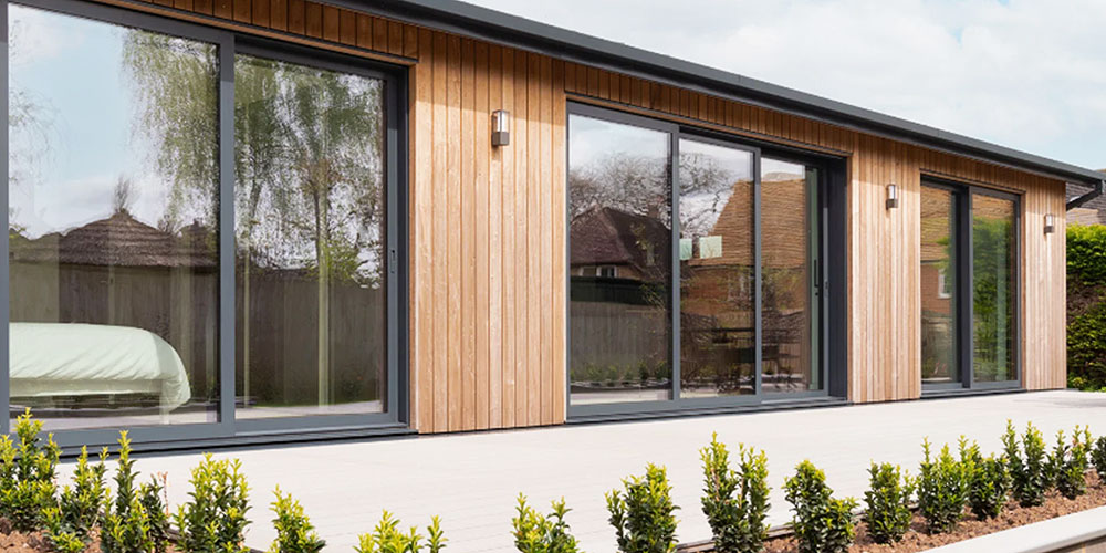 Dark aluminium sliding doors fitted to a timber garden building