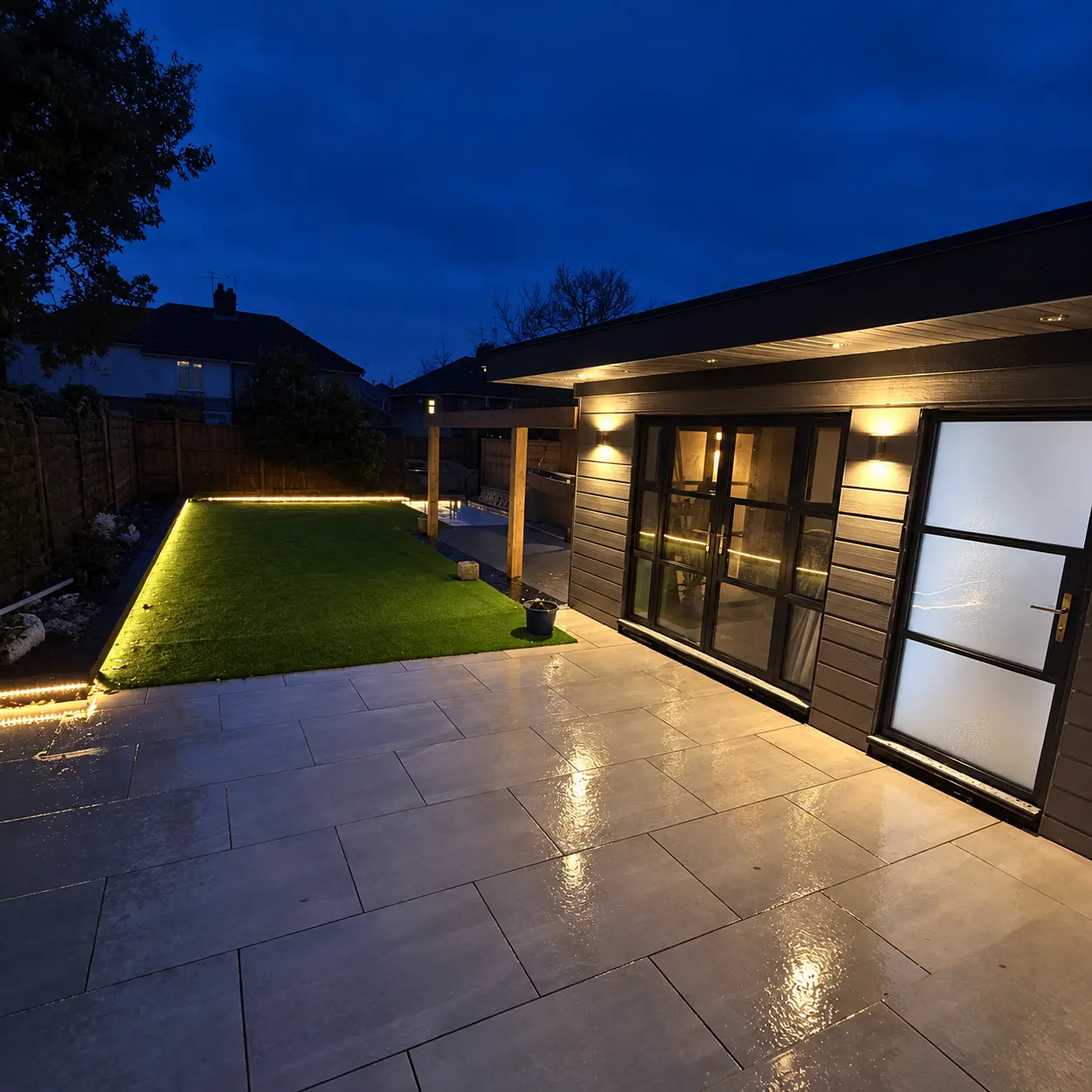 Converted garage with illuminated heritage-style aluminium doors at night