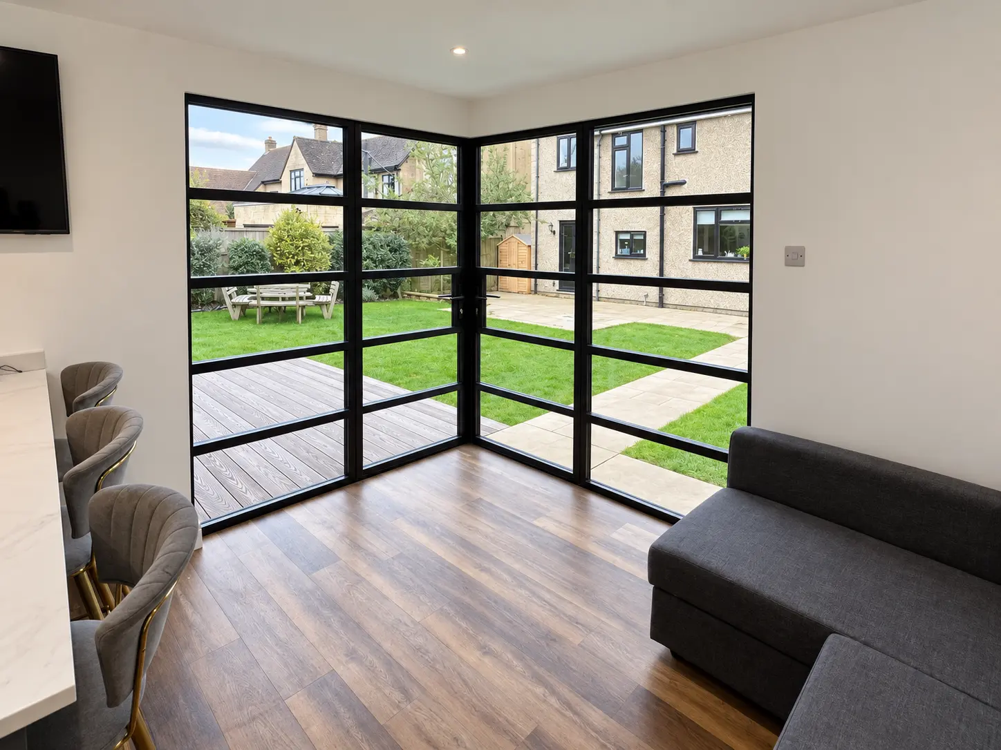 Internal view through jet-black heritage aluminium corner glazing towards the garden